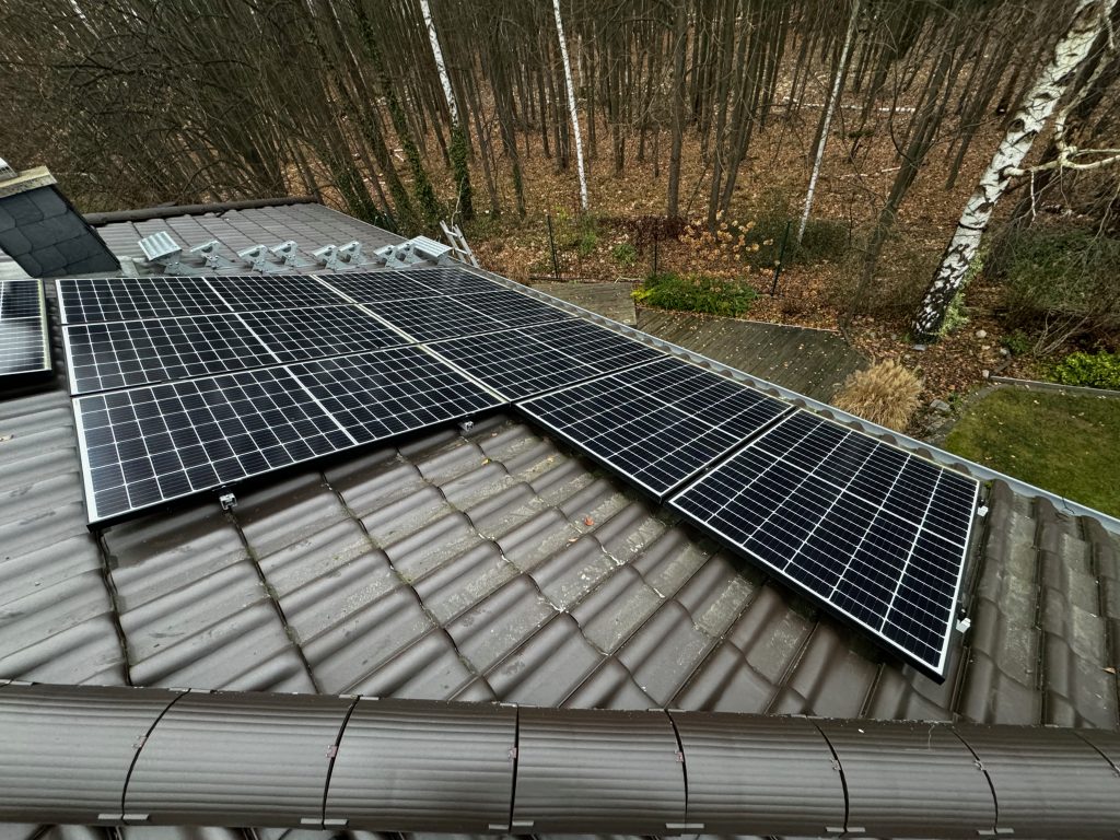 Ansicht einer PV-Anlage mit 8 Modulen auf einem grauen Dach mit Bäumen im Hintergrund