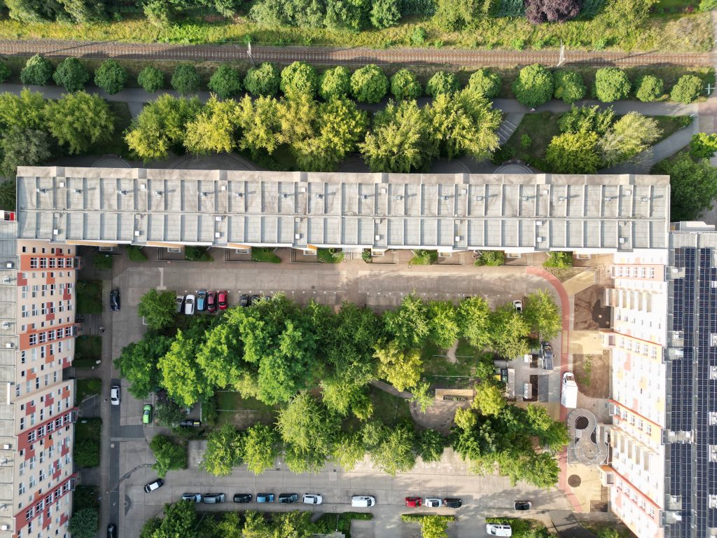 Luftansicht dreier Mehrfamilien-Häuserblocks in einer U-Anordnung mit einem begrünten Innenhof und grüner Umgebung