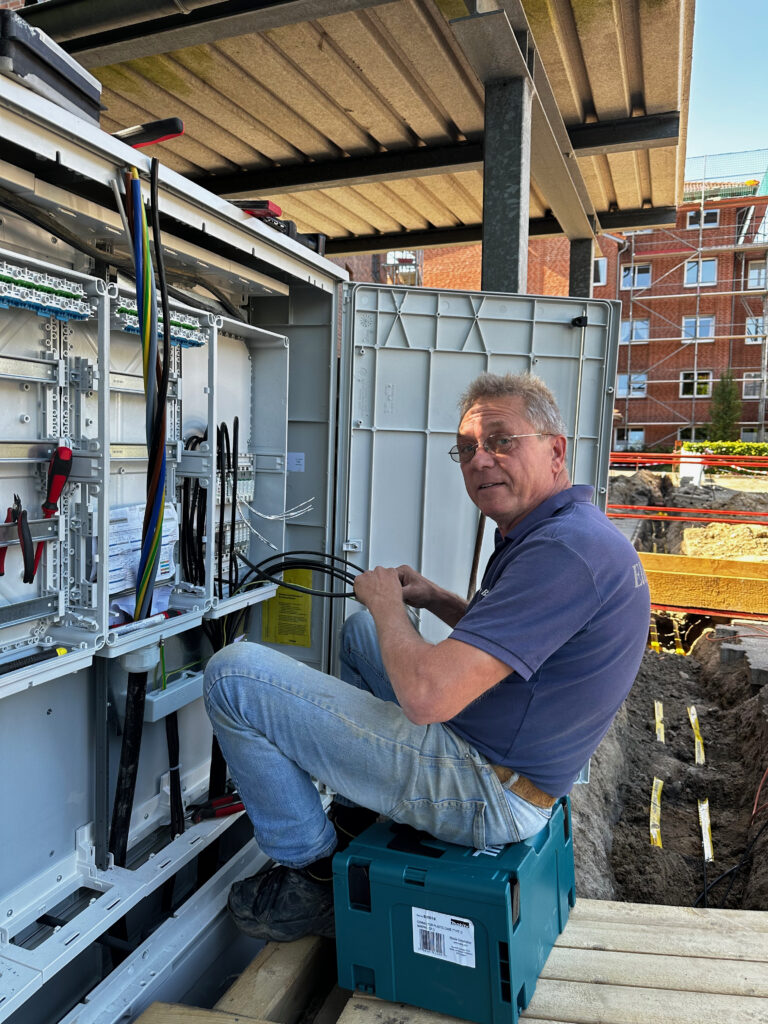 Ein Elektriker sitzt vor einem Sicherungskasten