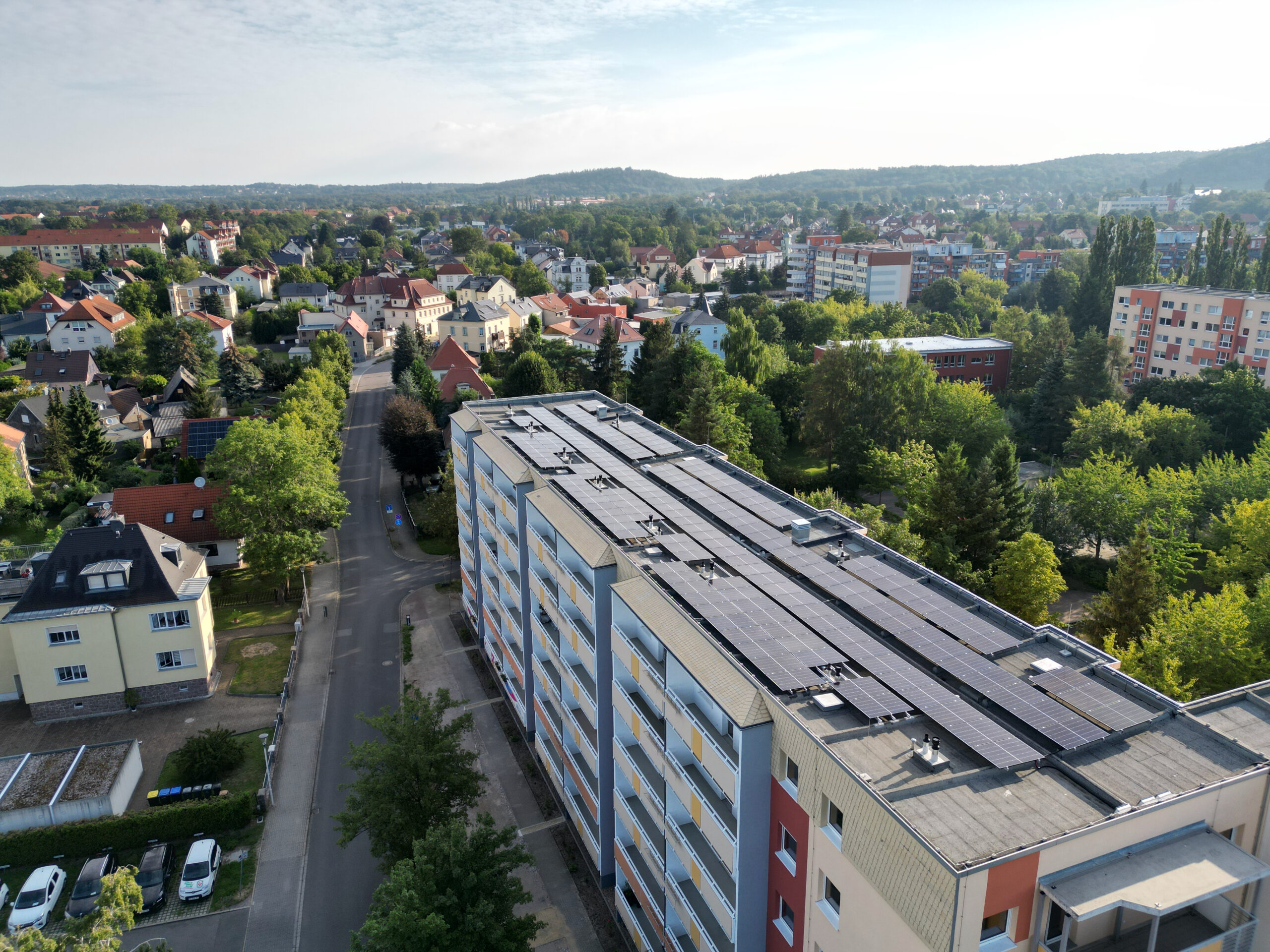 Ansicht eines lange Häuserriegels mit mehreren Mehrfamilienhäusern. Auf dem Flachdach befindet sich eine PV-Anlage, die für Mieterstrom genutzt wird.
